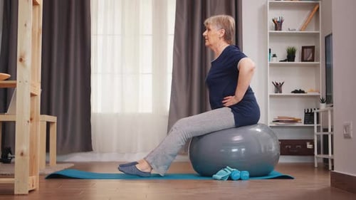 Mature Woman Seated on Exercise Ball at Home