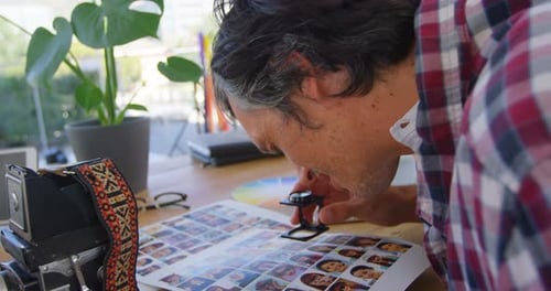 Fotógrafo masculino revisando fotos con lupa