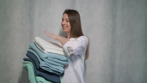 Young Woman Holding a Stack of Fresh Towels