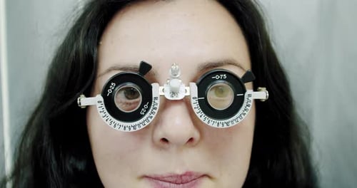 Nahaufnahme der Sehkraft für junge Frauen mit optischem Phoropter. Frau macht Sehtest langsam