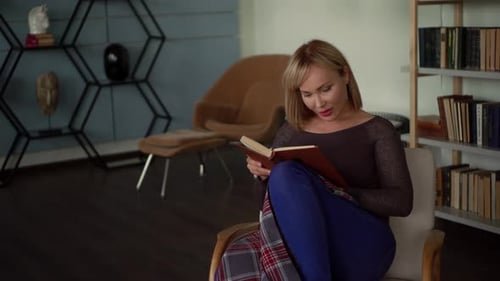 Woman Reading Book Relaxing in Chair at Home