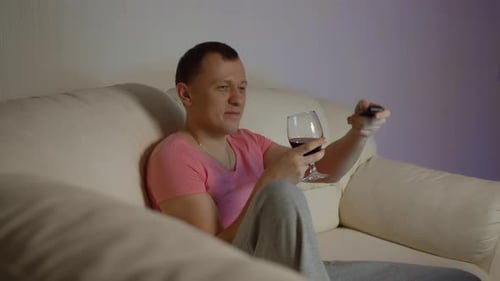 Man Drinking Wine Watching TV on Couch at Home