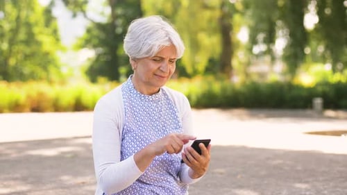 Happy Senior Woman with Smartphone at Summer Park 24