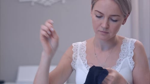 Junge Frau näht Kleidung mit einer Nadel