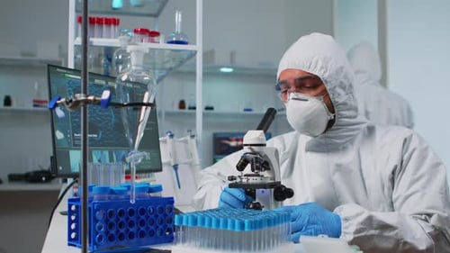 Biologe Doctor Coverall Überprüfung der DNA-Probe mit einem Mikroskop