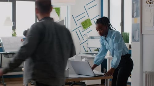 African American Woman Using Laptop to Design Building Model and Blueprints Plan