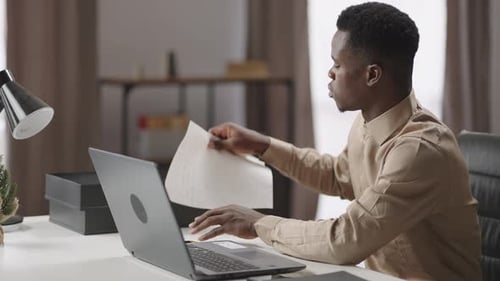 Young Adult Reviews Documents at Desk