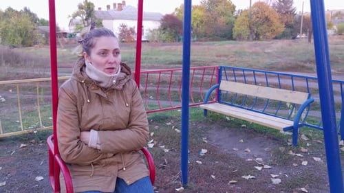 Woman Sits on a Swing at an Empty Playground