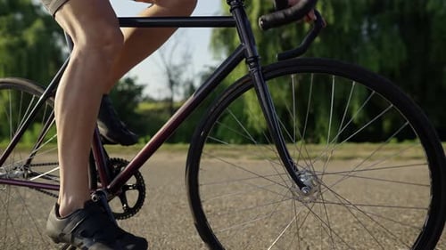 Nahaufnahme von Fahrradrädern, die sich drehen, während ein kaukasischer Sportler im Freien mit dem Fahrzeug fährt