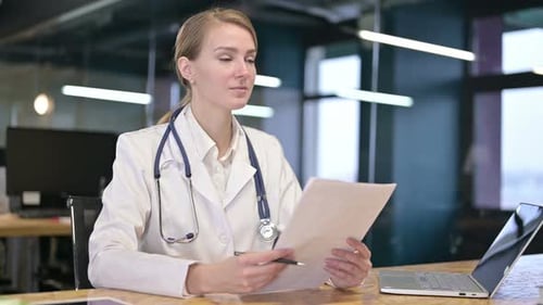 Cheerful Young Female Doctor Giving Documents To Client
