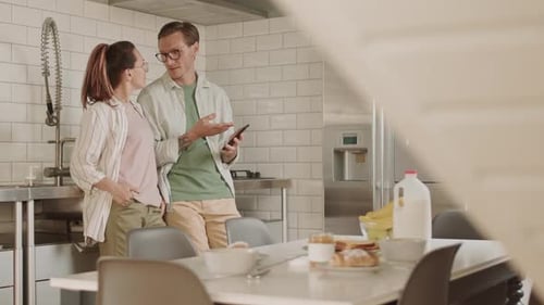 Couple Using Smartphone in Modern Bright Kitchen