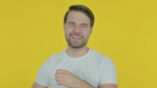 Enthusiastic Man Dancing Happily on Yellow Backdrop