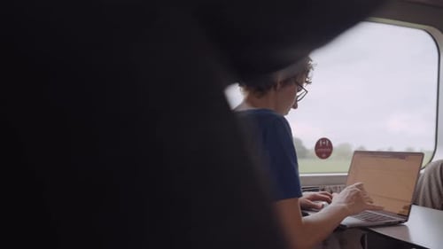 Femme à lunettes travaillant sur un ordinateur portable en allant en train