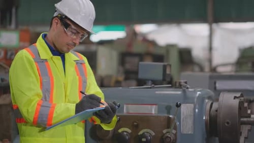 Technician or factory worker man with white helmet and bright yellow uniform check and maintenance