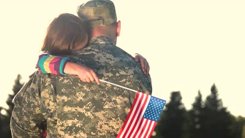 Soldier in Camoubackgrounde Hugging Daughter Outdoors, Back View.