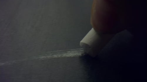 Chalk Drawing a White Line on Dark Gray Surface