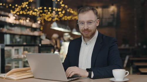 Portrait of Businessman Looking at the Camera While Working in Cafe with Laptop