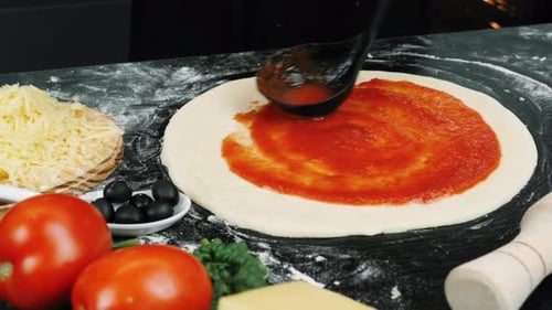 Hand verteilt Tomatensauce auf rohen Pizzateig