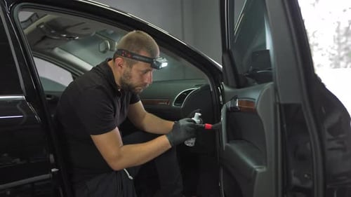 Man Carefully Cleans Car Interior with Detailing Brush
