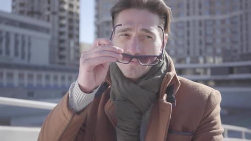 Man Putting on Sunglasses in Urban Environment