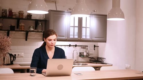 Woman Using Laptop Computer in Modern Kitchen