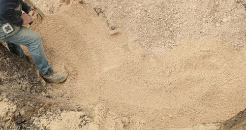 Construction Worker Shovels The Soil To Cover The PVC Pipe During Construction Work In Portugal. sta