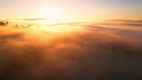 4K aerial view over a misty mountainous area. The great golden sun in the morning
