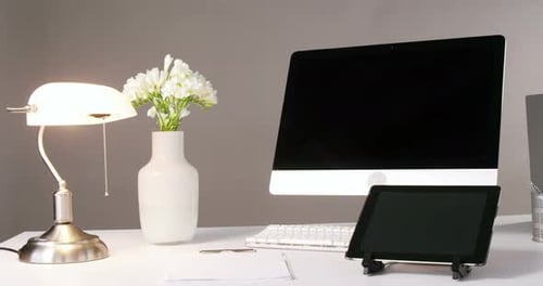 Computer, digital tablet, table lamp and flower vase