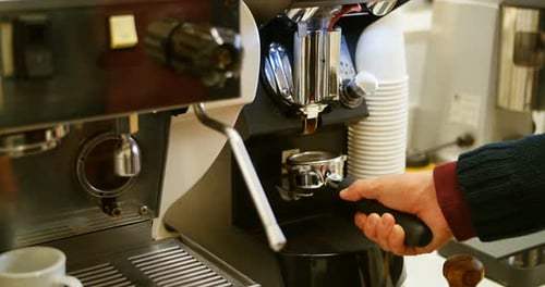 Man holding portafilter filled with ground coffee in cafe