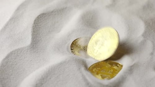 Bitcoin Cryptocurrency Gold Coins Fall on Dry White Sand