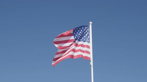 American Flag Waving Proudly Against Blue Sky