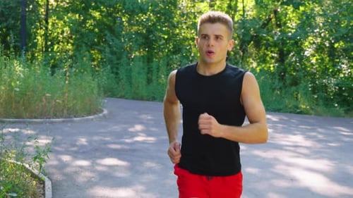 Slow Motion Man Breathing Hard While Running in Park