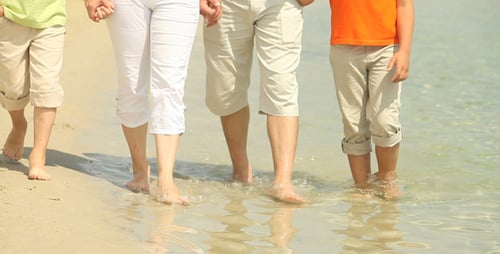Family Walks Barefoot Along Sandy Beach Shoreline