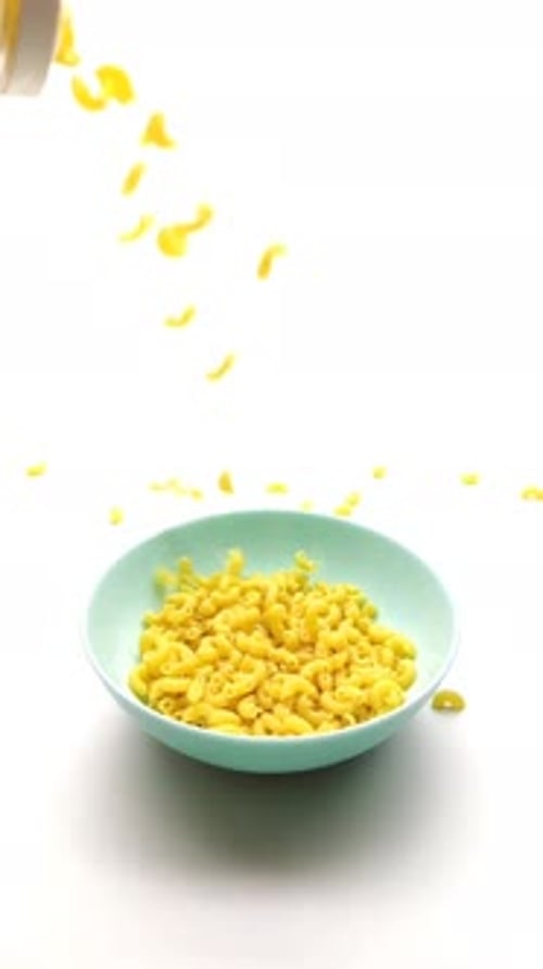 Raw Macaroni Pour Out on a Blue Plate Slow-down, Close-up