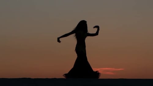 Girl Is Dancing Belly Dancing Against the Beautiful Sunset on the Beach. Silhouettes
