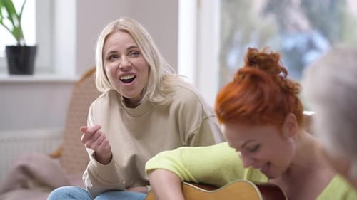 Women Sing and Play Guitar Together Indoors