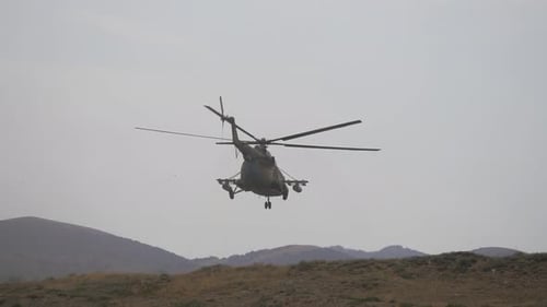 Military Helicopter Ascends Over Hilly Terrain