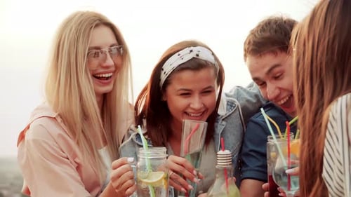 Young Adults Laughing Together with Drinks Outside