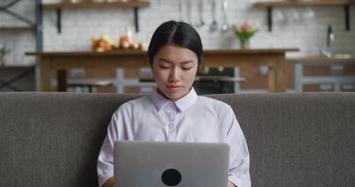 Woman Working on Laptop at Home on Sofa