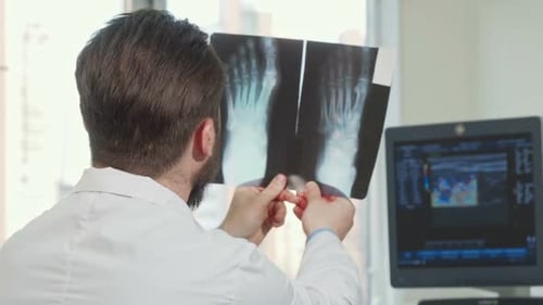 Rückansicht eines männlichen Arztes beim Blick auf Fußröntgenaufnahme eines Patienten