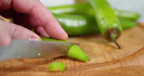 Male Hand with a Knife Cut the Green Chili Pepper.