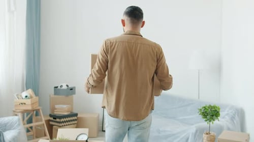 Back View of Middle Eastern Man Carrying Cardboard Boxes During Relocation to New Apartment