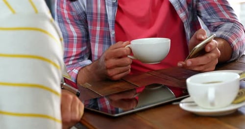 Adults Use Technology and Drink Coffee at Cafe