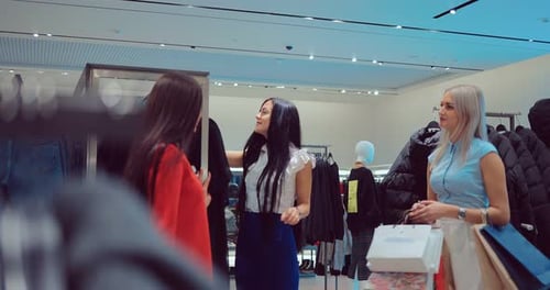 Girl Chooses Clothes in the Store and Consults with Her Friends