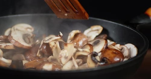 The Mushrooms in the Pan Stir with Spatula with Hot Steam.