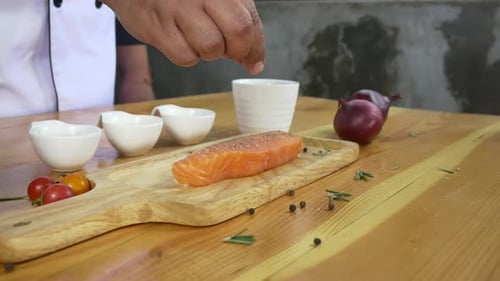 chef or cook seasoning fresh chunk of deli piece of beef with sea salt and grounded spicy peppers.