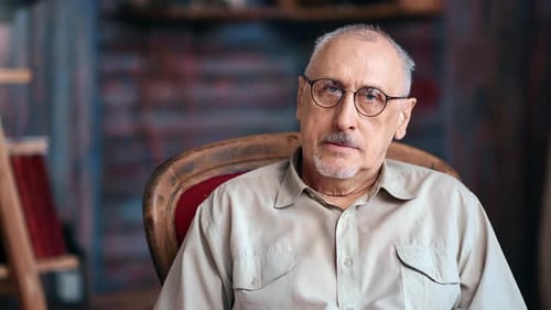 Man with Gray Hair Sits Calmly in Chair