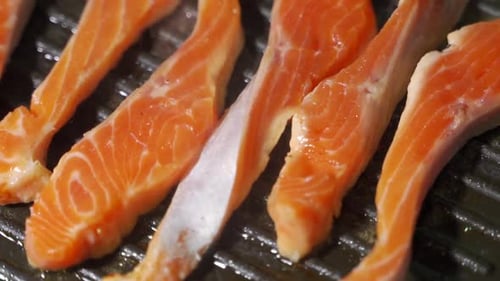 Homemade Fish Meal. Piece of Salmon or Trout Fillet Frying on Grilled Pan.