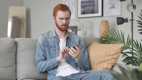 Man Using Smartphone Sitting on Couch at Home