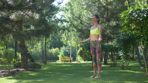 Woman Lifting Weights in a Park on a Sunny Day